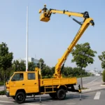 Грузовая автовышка желтого цвета с четырехдверной кабиной и поднятым подъемником на городской улице.